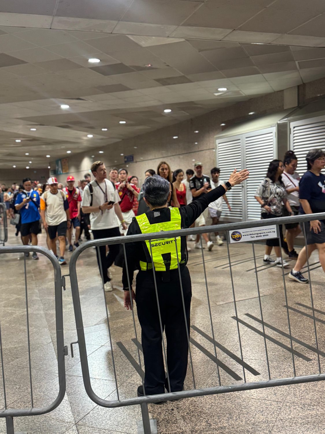 A Hawkeye officer in a hi-visibility vest directing a crowd at a Singapore event