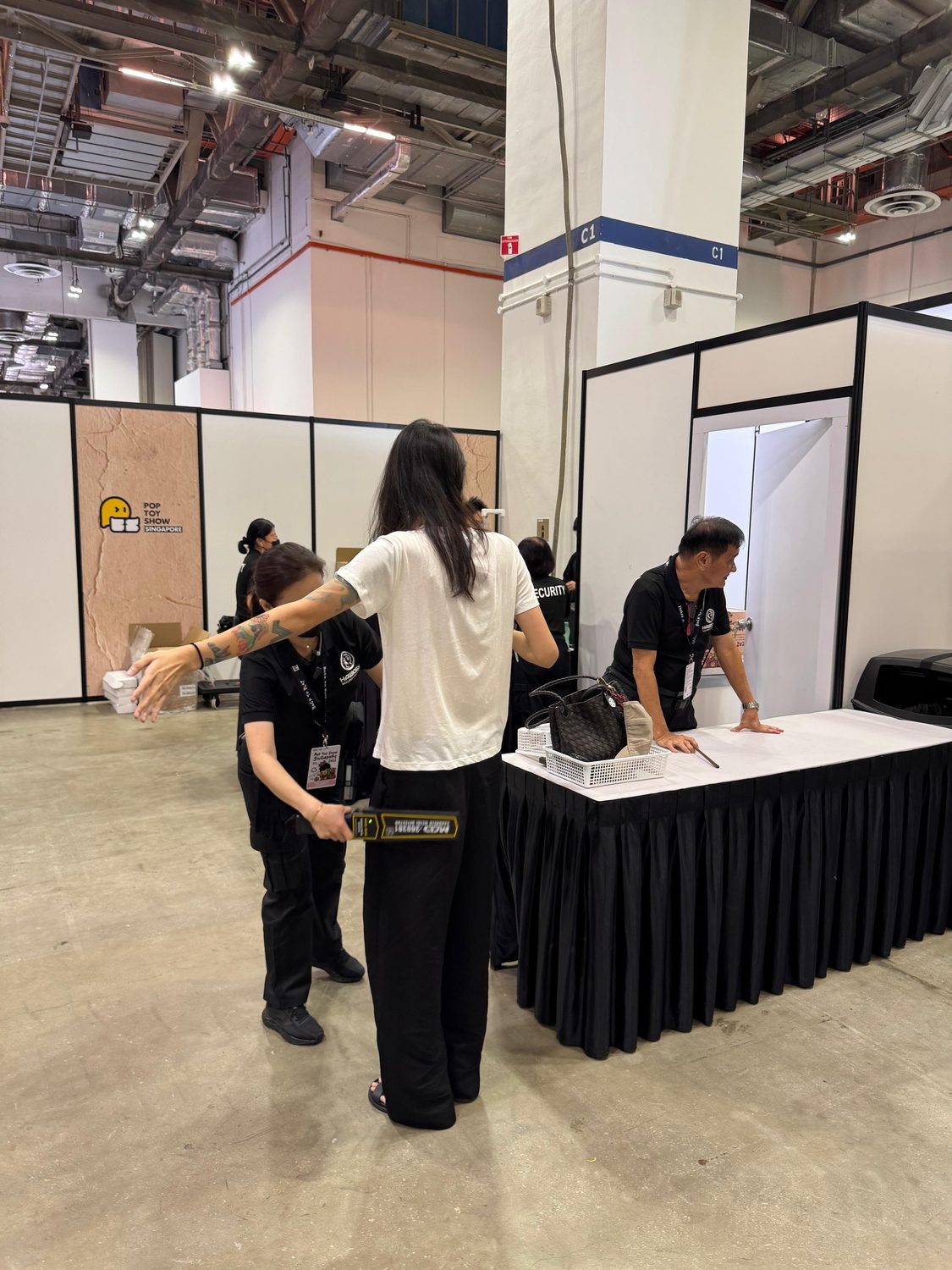 A Hawkeye officer screening an arriving attendee with a hand-held detector